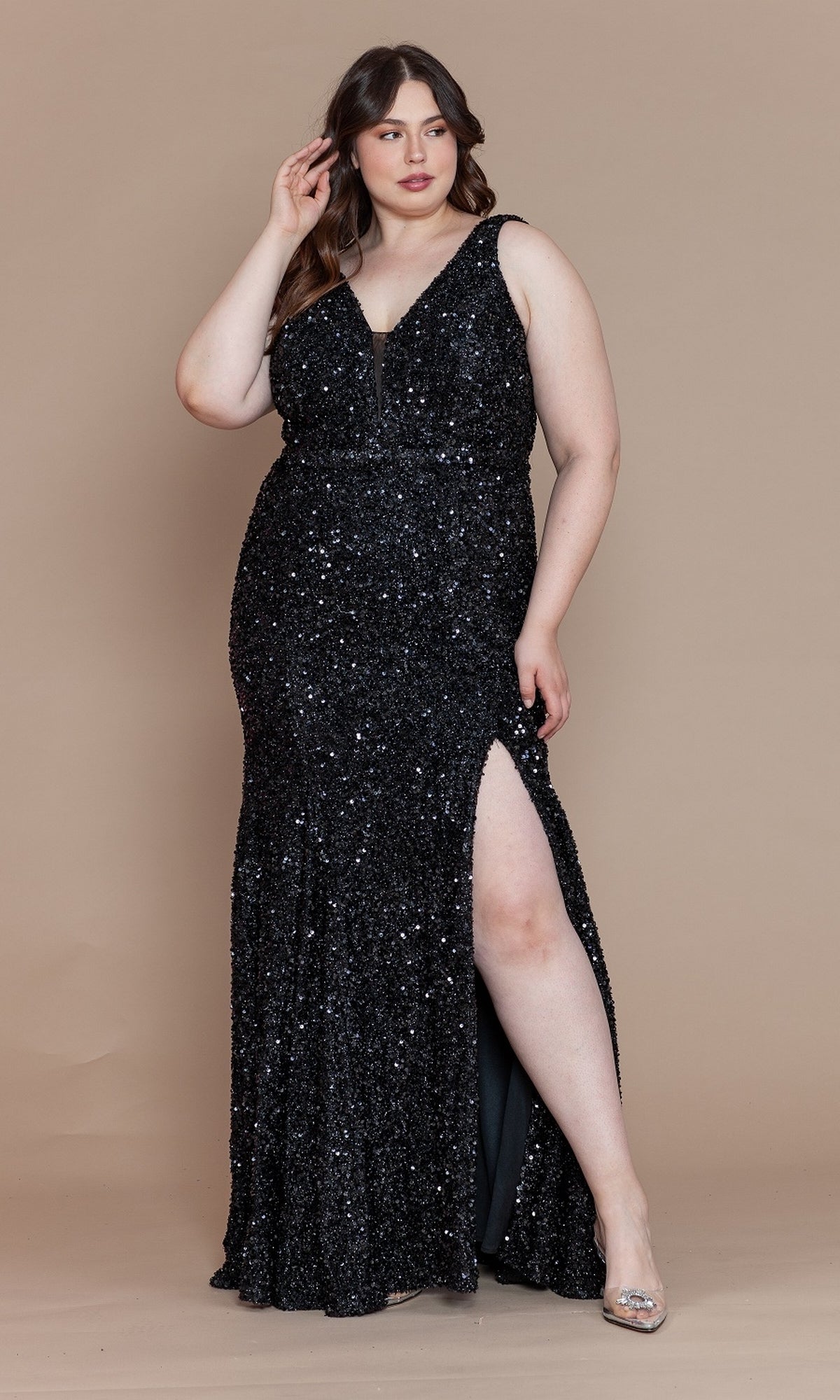 A woman models the Velvet-Sequin Plus-Size Long Prom Dress W1122, featuring a sleeveless, floor-length silhouette with a deep V-neckline and thigh-high slit, posing elegantly against a beige background.